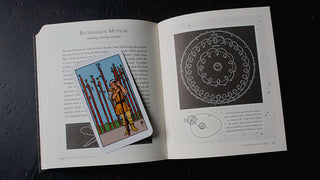 an image of the Raider-Waite Nine of Wands Tarot Card atop an astronomy book