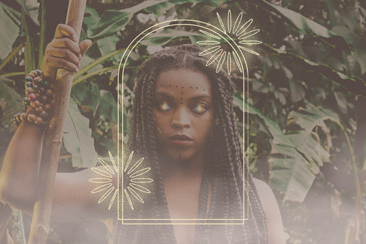 A black female Ancestress stands with a wooden staff in a moody forest with eyes illuminated by a rainbow light 