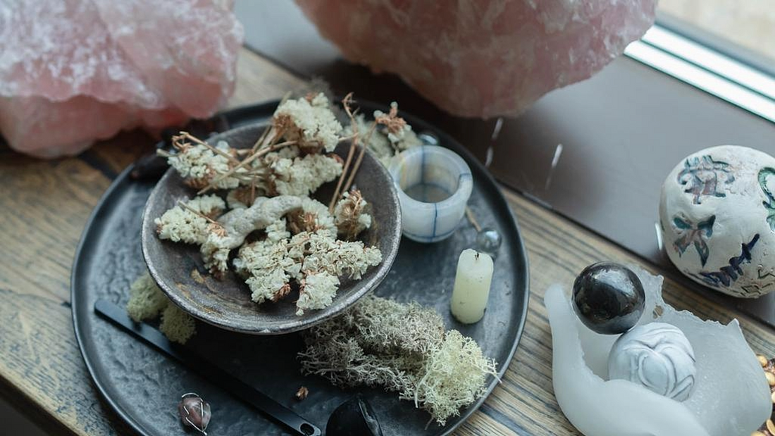 A serene new moon ritual setup with crystals, dried herbs, and candles, reflecting the spiritual practices of the Quickening New Moon.