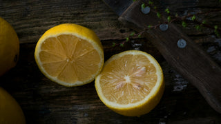 A halved lemon rests on a rustic wood table.
