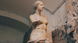 Classic marble statue of Aphrodite, Greek goddess of love and beauty, positioned against a vintage architectural backdrop.