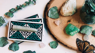 The last image depicts a tarot spread on a wooden surface surrounded by various stones and a butterfly, symbolizing transformation and change.