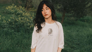 Harvest Moon in Pisces: A woman in a soft, natural setting wearing a shirt with an illustration of Plato, reflecting introspection and the merging of the intellectual with the spiritual.