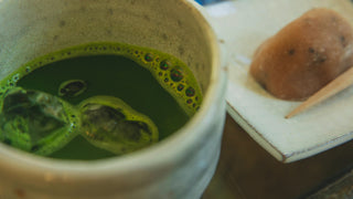 a cup of matcha sits next to a type of japanese sweet called "wagashi" which is usually consumed alongside matcha 