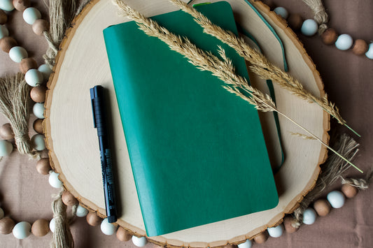 A green Journal, black pen, on cut wood with beads