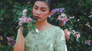 A woman in a floral dress stands in contemplation among vibrant flowers, evoking the introspective and analytical qualities of Virgo during the Snow Moon.