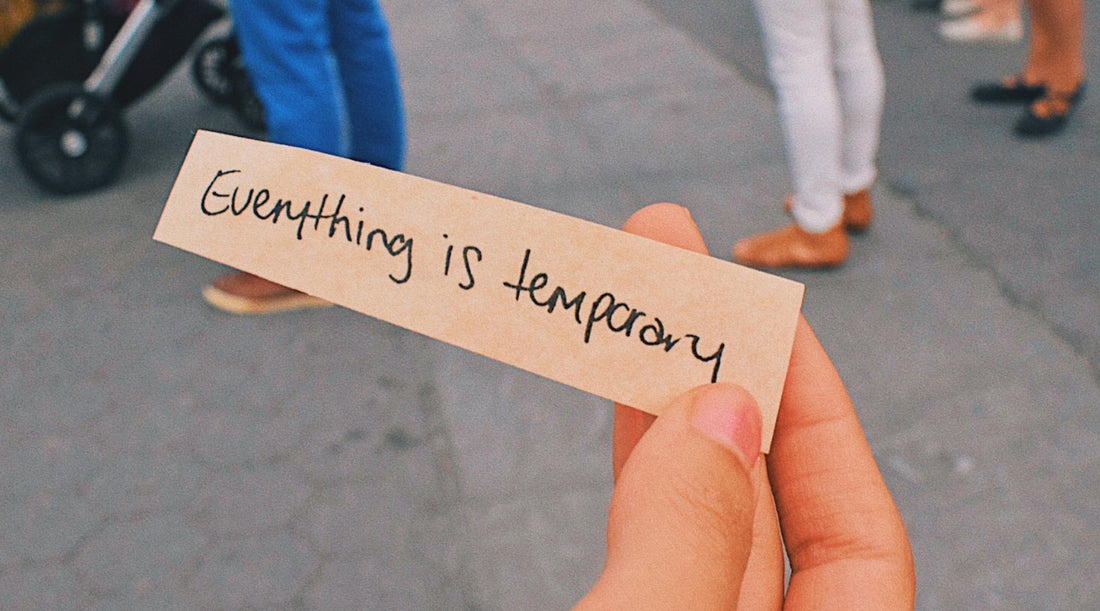 A hand gently holds a piece of paper with the handwritten message 'Everything is Temporary', serving as a soothing reminder during the chaos of Mercury retrograde that challenges are transient and resilience and patience are key.