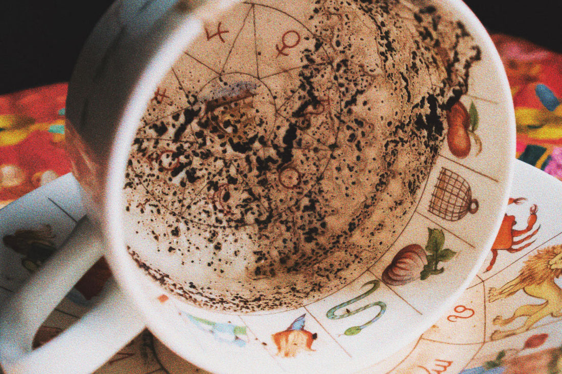 A Teacup lays on its side displaying coffee grounds in a unique pattern on its insides. 