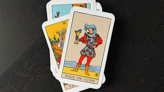 raider waite page of cups card against a dark wooden background