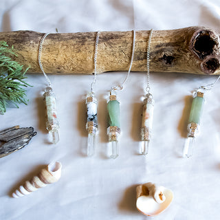 Crystal Quartz Point Pendulum Collection displayed next to seashells and driftwood